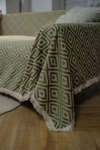 Detail of green and beige jacquard geometric throw blanket with fringe tassels