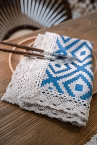 Close-up of geometric jacquard table runner with delicate lace trim and cotton linen texture