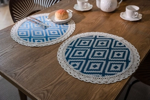 Detail of round dining placemats with blue geometric jacquard and white crochet lace edges