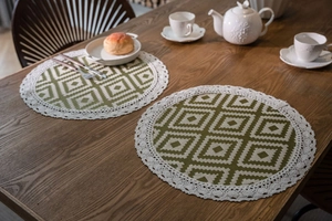 Close-up of olive green placemat with white geometric jacquard pattern and crochet lace edge