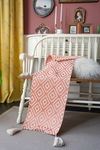 Detail of orange and beige geometric diamond table runner with handcrafted white tassels