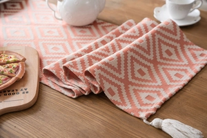 Detailed view of Nordic orange jacquard table runner with geometric patterns and white tassels