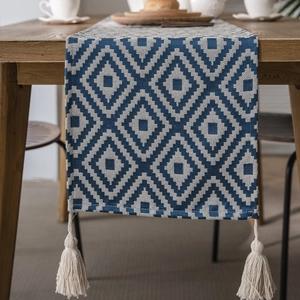 Nordic blue and white geometric table runner with tassels on dark wood table