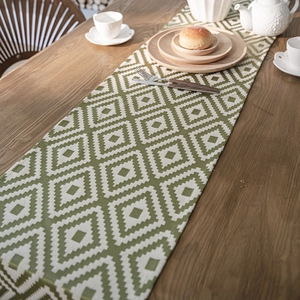 Nordic geometric jacquard table runner with green and white diamond patterns on a wooden table