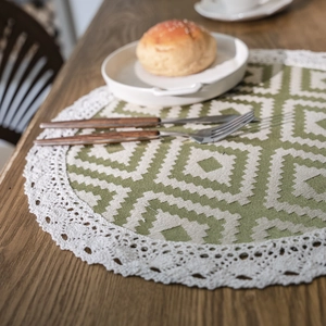 Nordic orange geometric woven round placemat with white lace trim on wooden dining table