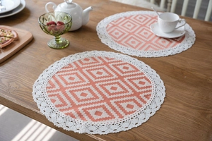 Detail of round orange geometric dining placemats with elegant white lace borders