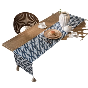 Nordic geometric blue and white diamond pattern table runner with tassels on a wooden table