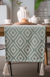 Detailed close-up of geometric diamond jacquard pattern and handmade tassels on table runner