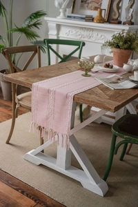 Close-up of pink Nordic table runner featuring woven white lines and fringe details
