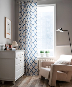 Detailed close-up of blue geometric diamond pattern curtain fabric with beige fringe tassels