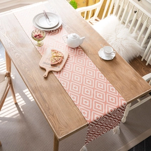 Nordic orange geometric jacquard table runner with white fringe on a wooden table