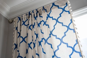 Close-up of blue geometric lattice pattern fabric with decorative white tassels