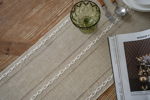Close-up of beige jacquard table runner with embroidery on natural wood dining table