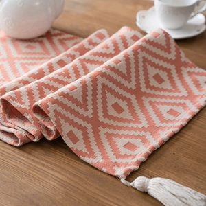 Bohemian orange geometric jacquard table runner with decorative tassels on wood table