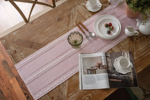 Detailed close-up of pink textured fabric table runner with white braided embroidery lines