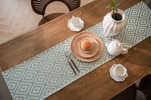 Close-up of mint green geometric jacquard table runner with fringe on dark wood table