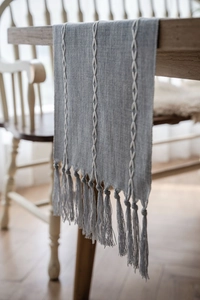 Detail of Nordic jacquard table runner with white embroidery and soft grey-blue tassels