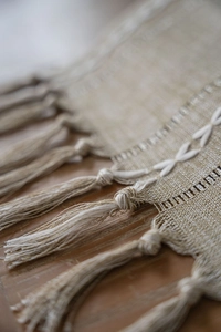 Close-up of bohemian table runner featuring white X-shaped embroidery and fringe tassels
