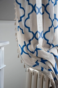 Detail of blue Moroccan geometric pattern curtain with off-white fringe tassel edges