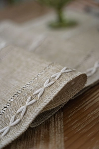Detail of beige jacquard table runner with white X-stitch embroidery and woven texture