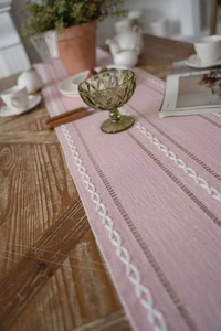 Detail of pink embroidered table runner with delicate hemstitch and petal texture patterns