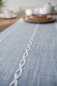 Detail view of light blue table runner featuring Nordic floral white embroidery texture