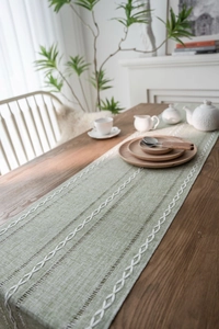Detail of light green table runner showing white diamond embroidery and textured fabric