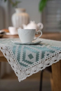 Close-up of mint green geometric jacquard table runner with delicate crochet lace edging
