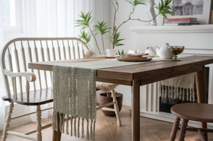 Detail of light green Nordic table runner featuring vertical stripes and long tassels