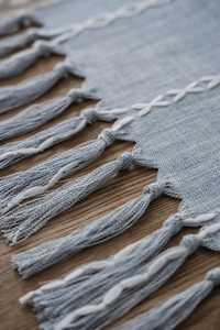 Detailed close-up of light blue Nordic table runner with woven texture and white fringe tassels