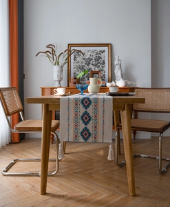 Detail of bohemian table runner with tassels and geometric patterns on a wooden table