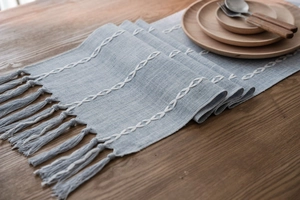 Detail of light blue Nordic table runner featuring chain embroidery and tassel fringes