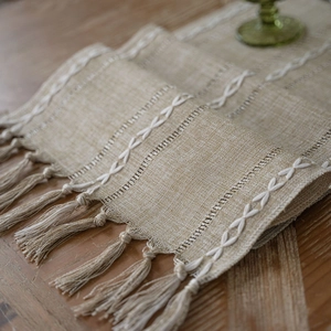 Nordic jacquard table runner with geometric embroidery and tassels on a wooden surface