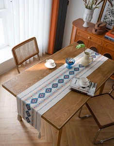 Detail of bohemian knit table runner with blue geometric patterns and tassels