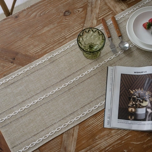 Nordic beige table runner with white geometric crochet lace on a rustic wooden dining table