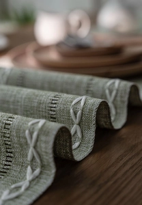 Macro shot of grass green linen textured table runner with white embroidered edges