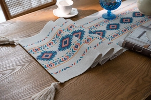 Close-up of bohemian table runner with geometric rhombus patterns and woven tassels