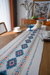 Close-up of bohemian table runner with orange and blue geometric diamonds and fringe