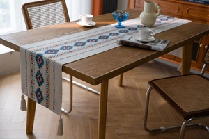 Detail of bohemian table runner with geometric rhombus pattern and decorative fringes