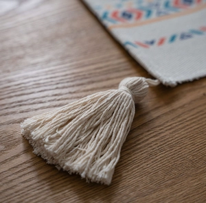 Close-up of bohemian table runner with thick cotton linen texture and orange blue tassels