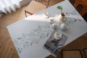 Detail of floral embroidery with green leaves and yellow berries on cotton linen tablecloth