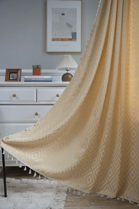 Yellow geometric diamond pattern curtain with white fringe edge in a cozy interior setting