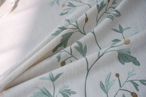 Detail of floral embroidery on off-white linen tablecloth with natural texture