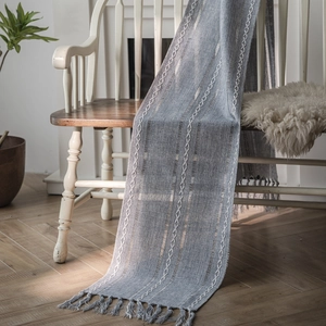 Blue Nordic table runner with white geometric embroidery and fringe on wooden bench