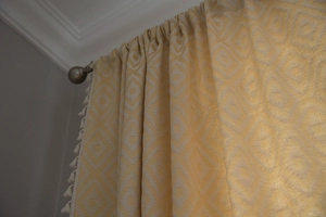 Detail of yellow geometric textured curtain with elegant white tassel trim for home