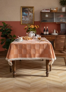 Nahaufnahme der orange-beigen Jacquard-Tischdecke mit rustikalen weißen Quasten und Gitter