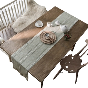 Green jacquard table runner with white geometric embroidery and tassels on wooden table