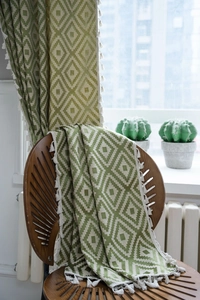 Detail of green and beige geometric diamond pattern fabric with white fringe tassels