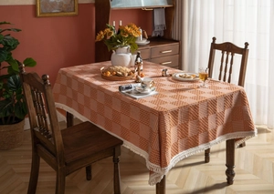Detail der orangebraunen karierten Tischdecke mit feinen weißen Fransenquasten