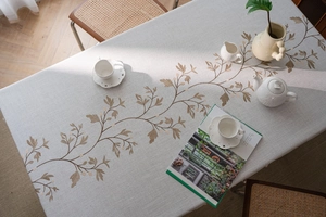 Detail of cream rectangular linen tablecloth with brown floral embroidery and natural texture
